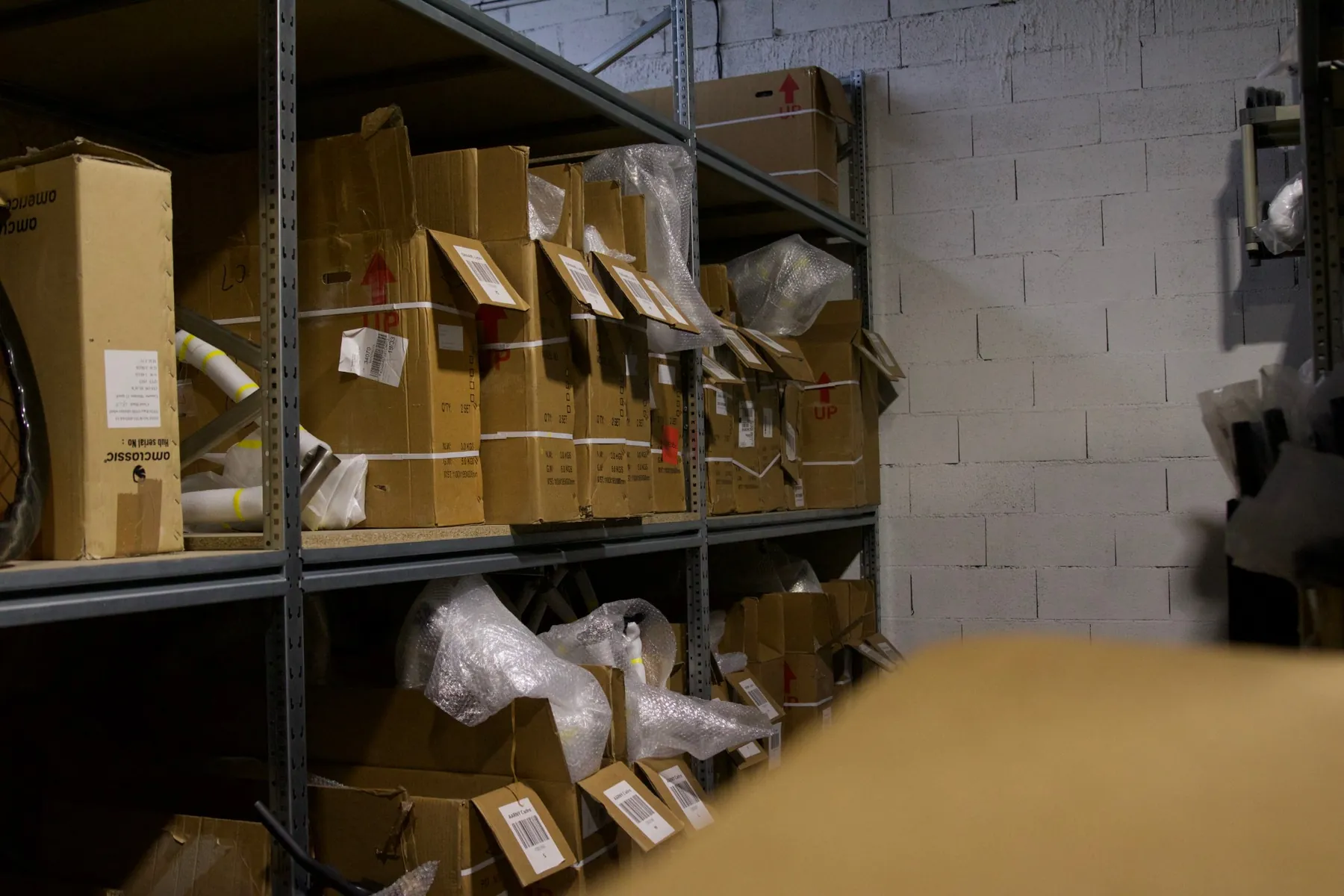 Shelves of boxed frames and parts in the stock room, each box tagged with a barcode.